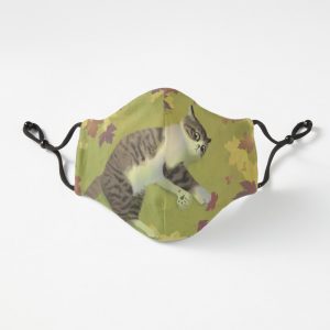 Fitted adjustable mask with a cat design. The cat is lying on a green grassy background surrounded by fallen autumn leaves.